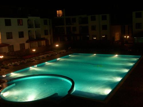 uma grande piscina azul à noite com edifícios em Complex Apolon em Nesebar