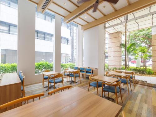 a dining room with tables and chairs and large windows at Nishitetsu Resort Inn Naha in Naha