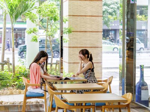 two women sitting at a table in a cafe at Nishitetsu Resort Inn Naha in Naha