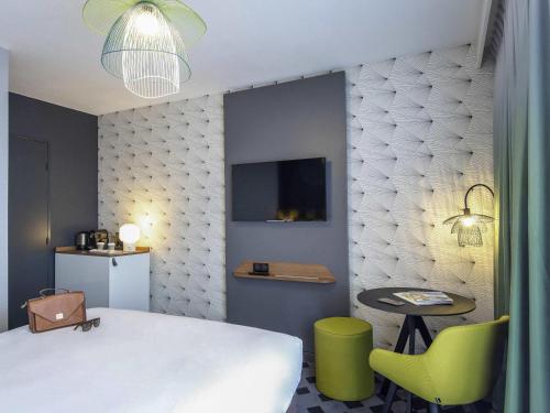 a bedroom with a bed and a table and a chair at Mercure Hyères Centre Côte d'Azur in Hyères