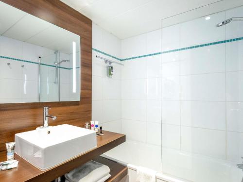 a white bathroom with a sink and a shower at Mercure Hyères Centre Côte d'Azur in Hyères