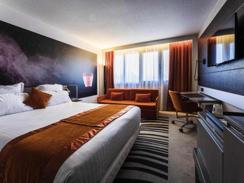a hotel room with a large bed and a desk at Novotel Orléans Saint Jean de Braye in Saint-Jean-de-Braye