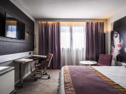 a hotel room with a bed and a desk at Novotel Orléans Saint Jean de Braye in Saint-Jean-de-Braye