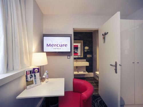 a living room with a red chair and a television at Mercure Saint Lô Centre in Saint Lo