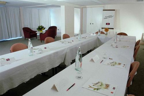a meeting room with white tables and chairs with bottles at Mercure Saint Lô Centre in Saint Lo