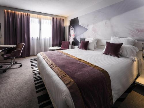 a hotel room with a large bed and a desk at Novotel Orléans Saint Jean de Braye in Saint-Jean-de-Braye