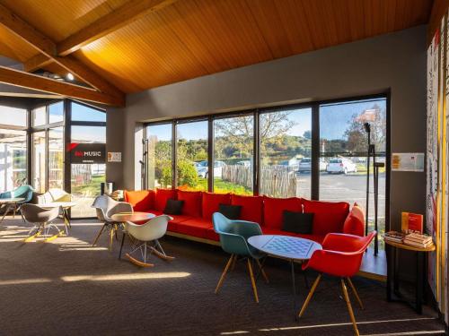 a lobby with a red couch and some chairs at Ibis Angoulême Nord in Champniers