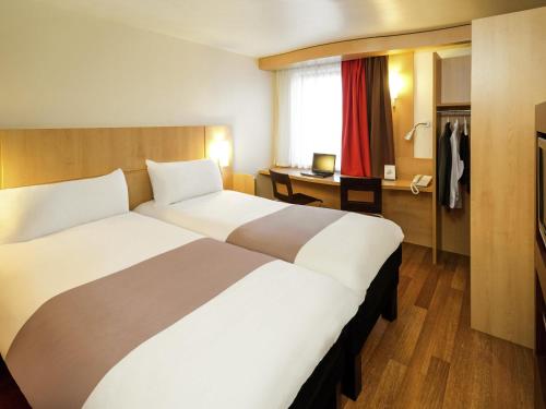 a hotel room with two beds and a desk at ibis Hotel Brussels Airport in Diegem