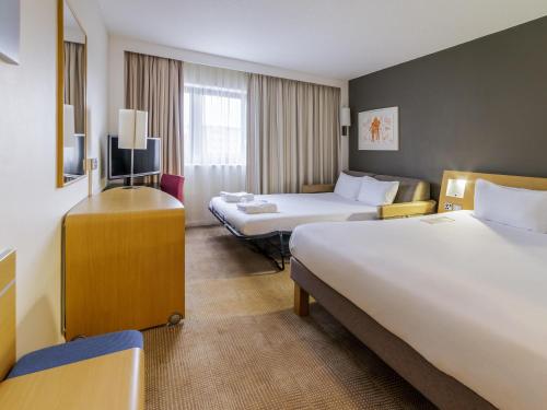 a hotel room with two beds and a television at Novotel Southampton in Southampton