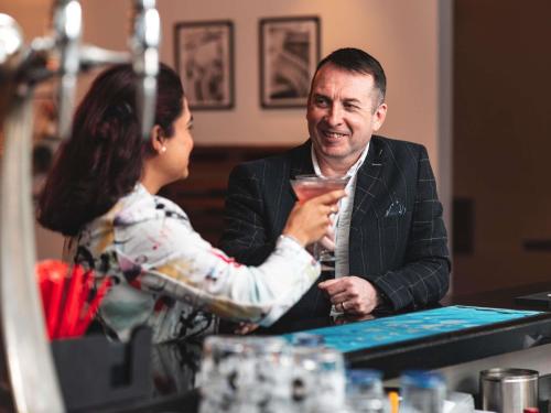 a man and a woman sitting at a table with a drink at Novotel Southampton in Southampton