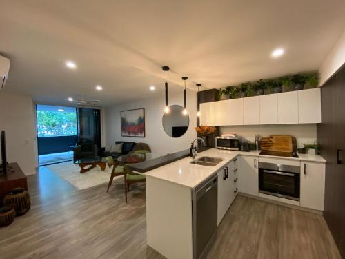 a kitchen with white cabinets and a living room at Urban Retreat Homestay - Shared Apartment with Queen Bed and Private Ensuite in Brisbane