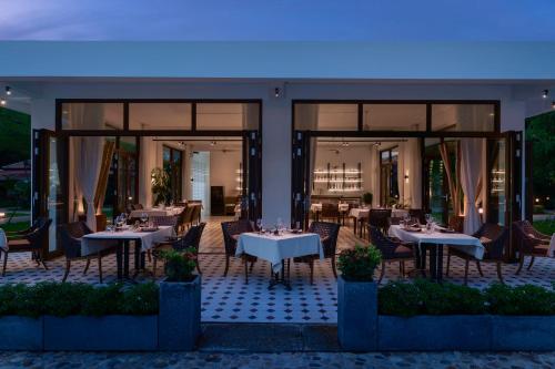 a restaurant with white tables and chairs and windows at Samanea Beach Resort & Spa in Kep
