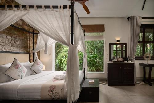a bedroom with a canopy bed with a window at Samanea Beach Resort & Spa in Kep