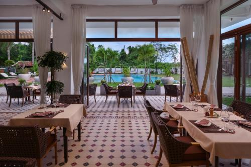 a restaurant with tables and chairs and a pool at Samanea Beach Resort & Spa in Kep