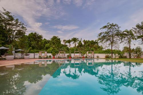 a swimming pool with chairs and trees in the background at Samanea Beach Resort & Spa in Kep
