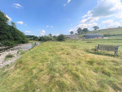 a bench sitting in a field next to a river at 5 Bed in Ingleton 90546 in Burton in Lonsdale