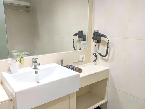 a bathroom with a white sink and a mirror at Horison Kota Lama Semarang in Semarang