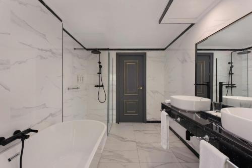 a bathroom with two sinks and a tub and mirrors at Eugenia de Montijo, Autograph Collection in Toledo