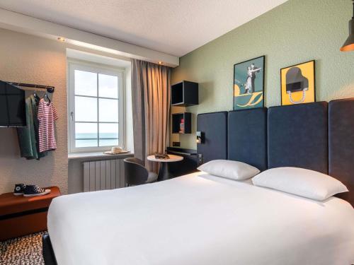 a hotel room with a large white bed and a window at ibis Saint Malo Plage in Saint Malo