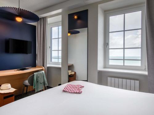 a room with a bed and a desk and windows at ibis Saint Malo Plage in Saint Malo