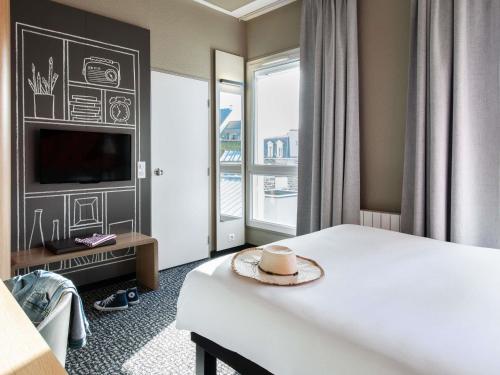 a hotel room with a bed and a large window at ibis Saint Malo Plage in Saint Malo
