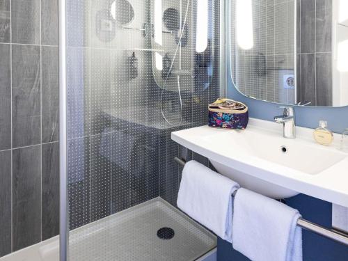 a bathroom with a shower with a sink and a mirror at ibis Saint Malo Plage in Saint Malo