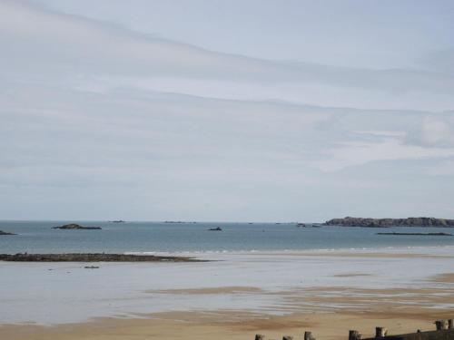 a beach with the ocean and rocks in the distance at ibis Saint Malo Plage in Saint Malo