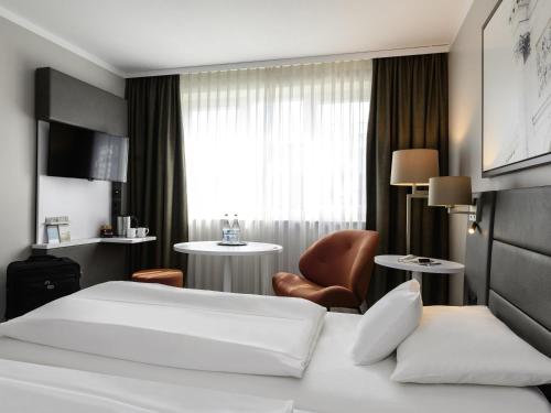 a hotel room with a bed and a chair at Mercure München City Schwabing in Munich