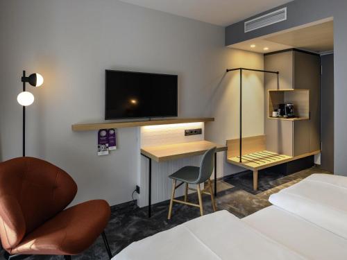 a hotel room with a bed and a desk with a television at Mercure München City Schwabing in Munich