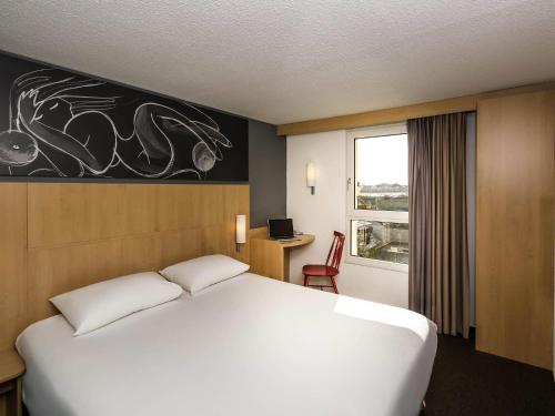 a bedroom with a large white bed and a window at Ibis Roscoff in Roscoff