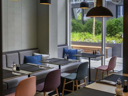 a restaurant with tables and chairs and a window at Mercure München City Schwabing in Munich
