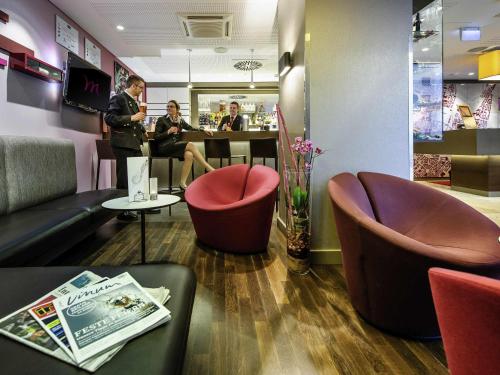 a restaurant with two people sitting in a waiting room at Mercure München City Schwabing in Munich