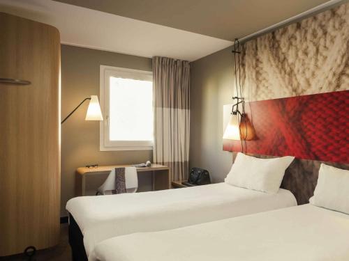 a hotel room with two beds and a desk at ibis Le Havre Centre in Le Havre