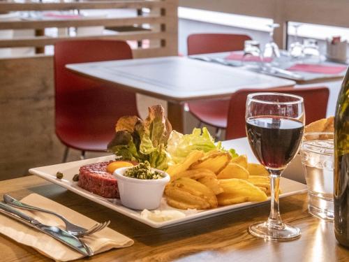 a plate of food on a table with a glass of wine at ibis Gap Centre in Gap