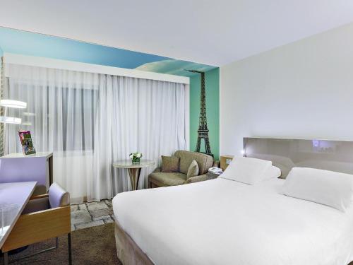 a hotel room with a large bed and a chair at Mercure Paris Vaugirard Porte De Versailles in Paris