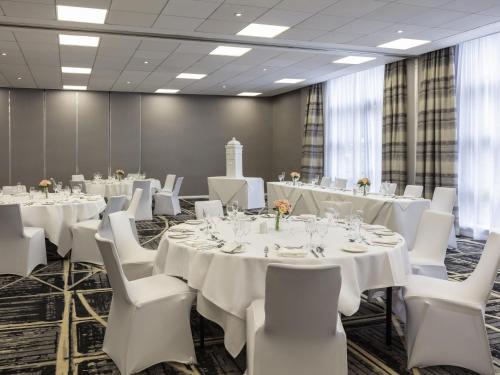 a conference room with white tables and white chairs at Novotel Newcastle Airport in Newcastle upon Tyne