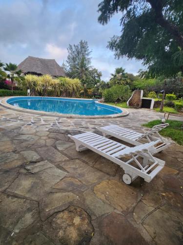 a pool with a chaise lounge in front of it at Villa Fortuna Malindi in Malindi