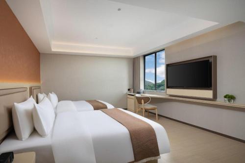 a hotel room with a bed and a flat screen tv at Immersing Hotel Guilin Two Rivers and Four Lakes Dongxi Alley in Guilin