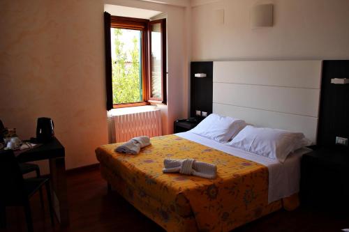 a bedroom with a bed with a yellow blanket and a window at Primavera Mini Hotel in Perugia