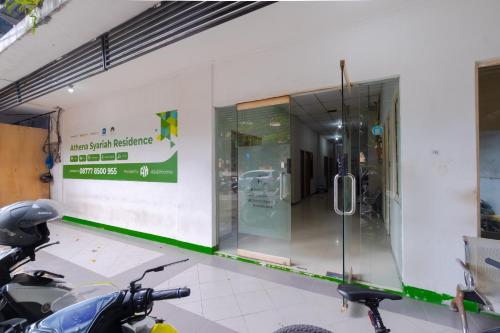 a motorcycle parked in front of a building with a glass door at Athena Syariah Residence in Tangerang