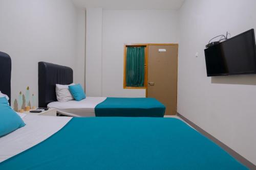 a room with two beds and a flat screen tv at Athena Syariah Residence in Tangerang