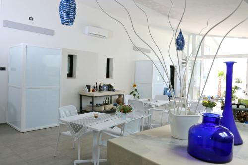 a room with white tables and chairs and a blue vase at La Bella Trani - Suites and B&B in Trani