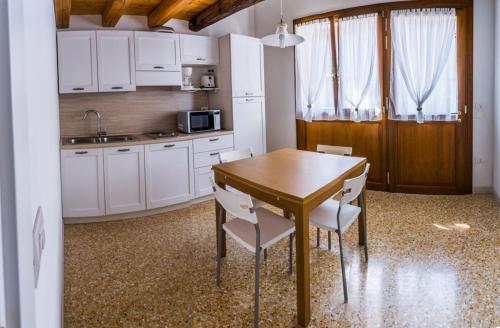 a kitchen with white cabinets and a wooden table and chairs at Agriturismo Dai Gobbi in Fara Vicentino