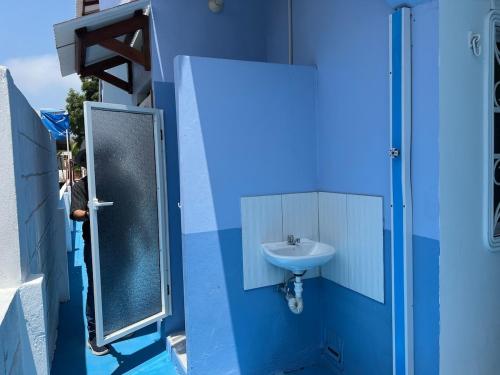 Un baño azul con lavabo y espejo. en Alojamiento en Shekinah House, en Data de Villamil