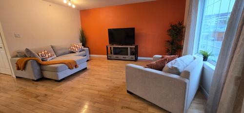 a living room with two couches and a flat screen tv at Northern Manor in Yellowknife
