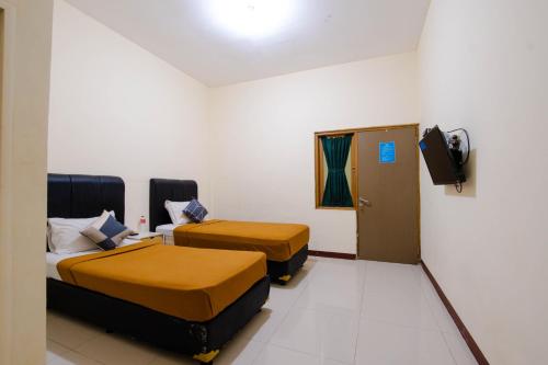a hotel room with two beds and a television at Athena Syariah Residence in Tangerang