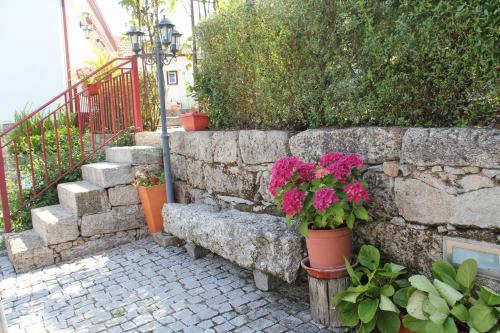 a stone retaining wall with a bench and flowers at O Aconchego das Raízes in Baião