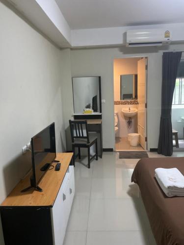a bedroom with a bed and a desk with a television at Suvarnabhumi Mansion in Samutprakarn