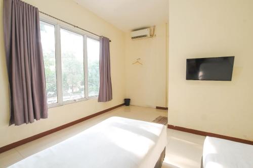 a room with a bed and a tv and a window at Athena Syariah Residence in Tangerang