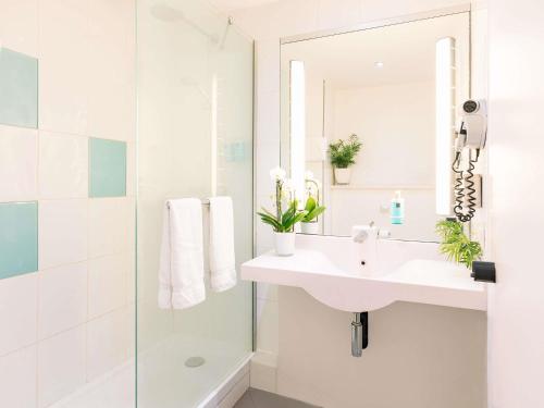 a white bathroom with a sink and a shower at Novotel Milano Linate Aeroporto in Milan